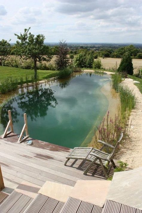 a large natural pool with greenery around and a wooden deck looks absolutely harmonious in the landscape and invites in