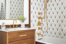 a mid-century modern bathroom with penny tiles, an accent wall in the shower, a stained vanity, gold fixtures