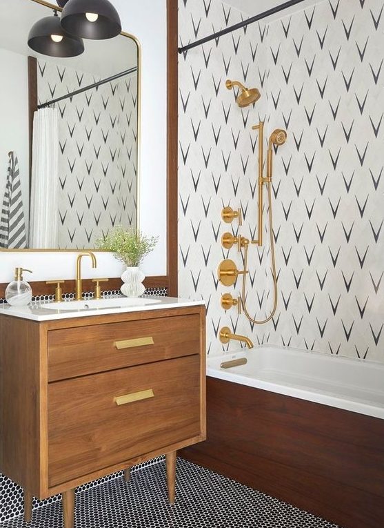 a mid-century modern bathroom with penny tiles, an accent wall in the shower, a stained vanity, gold fixtures