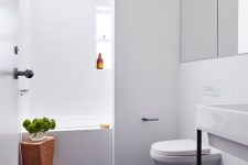 a minimalist bathroom with white walls and a black penny tile floor, a sink, a mirror wall and a cork stool