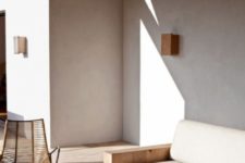 a minimalist neutral terrace with sleek furniture, a wooden table, a wicker chair and bright tableware for more interest