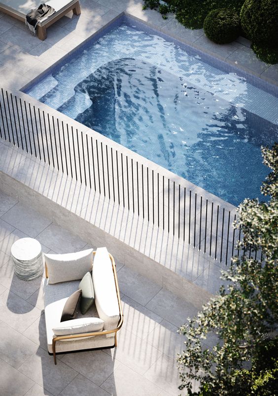 a minimalist outdoor space with a plunge pool clad in stone, loungers and chairs is a very lovely nook to have a rest in