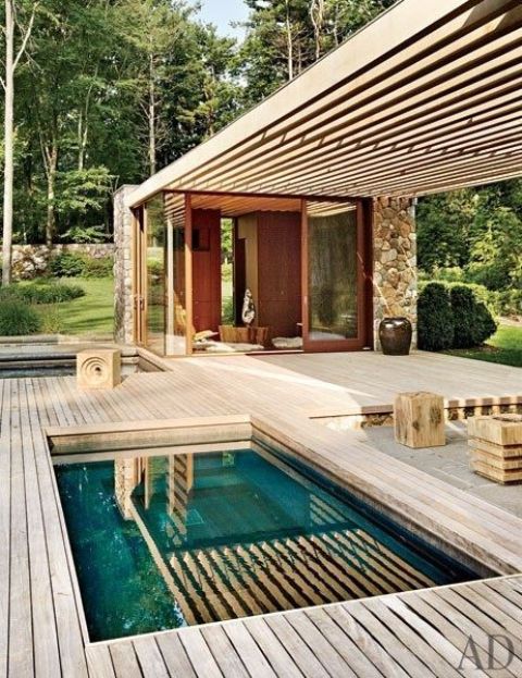 a minimalist wooden backyard with a roof, some furniture items, a built in plunge pool and a hot tub