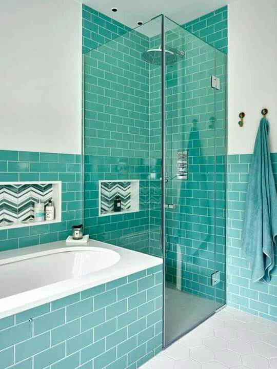 a modern bathroom clad with turquoise subway tiles, a shower space clad with glass, a tub clad with tiles