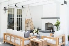 a modern neutral terrace with wooden furniture, a hanging rattan chair, a fireplace and greys feels very welcoming