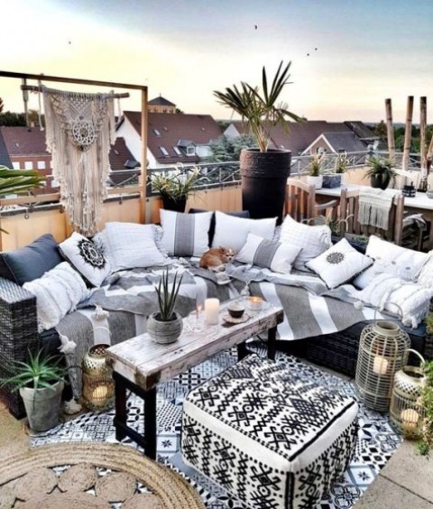 a monochromatic Moroccan rooftop terrace with striped and bold printed textiles, a macrame hanging and a wooden table