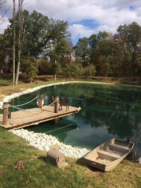 a natural swimming pond with rocks around and a wooden deck over it is a cool space to swim in and relax