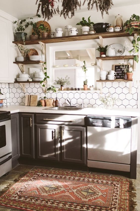 a neutral boho chic kitchen with a hex tile backsplash, a boho rug, potted greenery and open wooden shelving