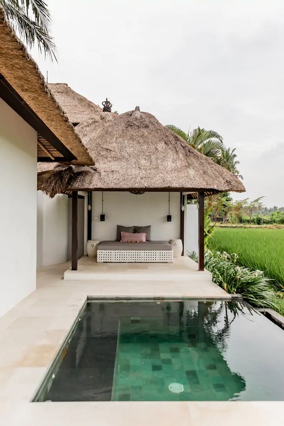a peaceful and welcoming outdoor space with a daybed under the roof for a day nap and a plunge infinity pool
