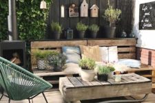 a rustic Scandinavian terrace with reclaimed wood furniture, a green chair, potted plants and birdhouses