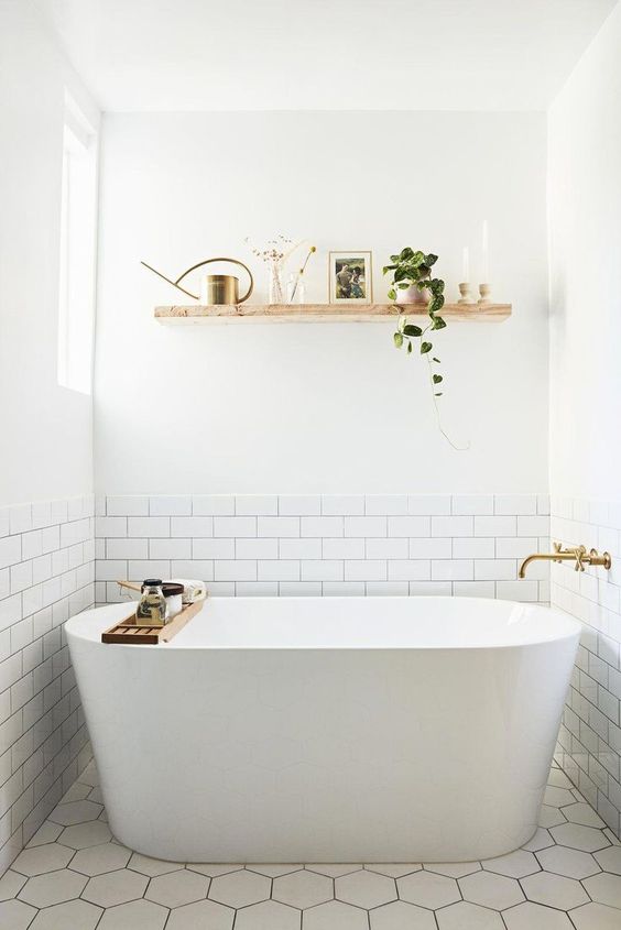 a serene bathroom clad with white subway and hex tiles, a shelf, a tub and brass fixtures is amazing