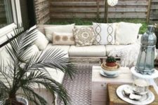 a simple neutral boho patio with printed textiles, potted greenery and wooden and wicker furniture