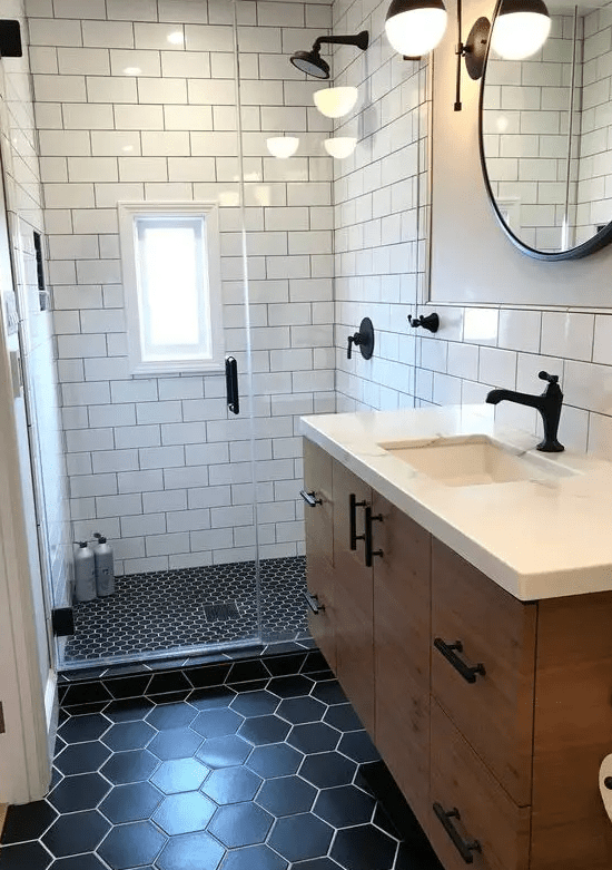 a small mid-century modern bathroom with white subway, black penny and hexagon tiles, a floating vanity, a round mirror and sconces
