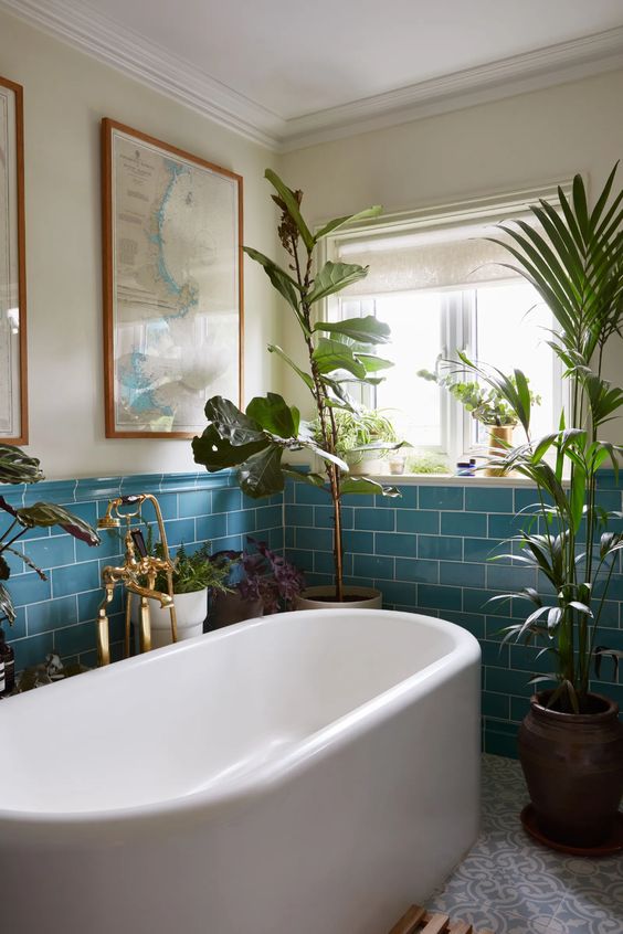 a stylish bathroom done with blue subway and printed tiles, a tub, lot sof potted plants and decor is amazing