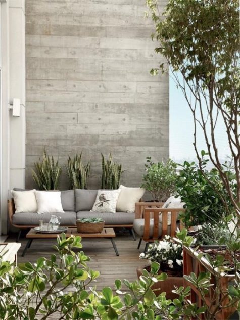 a stylish contemporary terrace with wooden furniture, greys and off-whites, potted greenery and plants