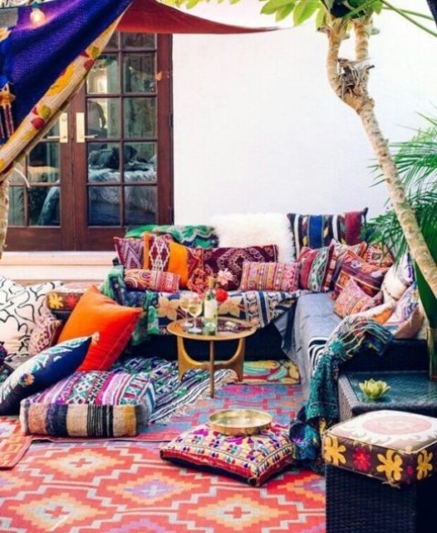 a super bright boho terrace with colorful textiles and lots of patterns and an L-shaped bench