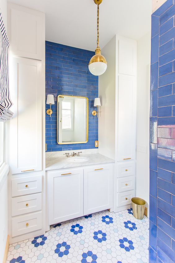 a super colorful bathroom accented with periwinkle subway tiles, hex ones, with white furniture and gold touches