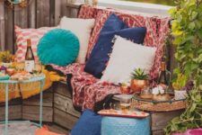a super colorful boho chic terrace with a wooden bench, colorful pillows and textiles plus some fabric baskets