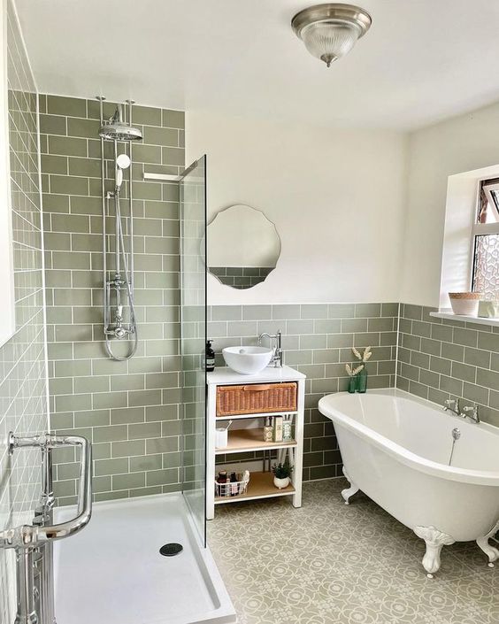 a vintage bathroom clad with olive green subway tiles, a shower space, a clawfoot tub, a vanity with storage space and a mirror