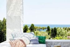 a welcoming Mediterranean terrace with white plaster, a large daybed with bright throws and a table