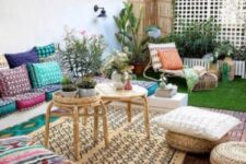 a welcoming boho terrace with colorful and printed pillows and cushions and rugs plus rattan furniture items