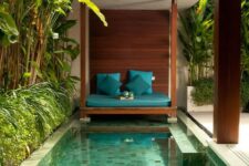 a welcoming tropical backyard with a rustic cabana, a small pool with mosaic tiles and built-in benches