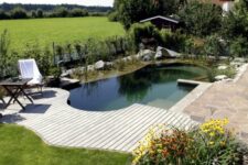 a wooden and stone deck with a small and cool natural swimming pond, just like a plunge pool and greenery
