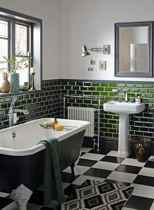 an elegant vintage bathroom clad with green subway and checked tiles, a black tub, a free-standing tub, some decor