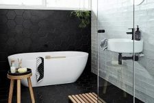 large scale black hex tiles cover the floor and go up the wall and contrast the white tiles