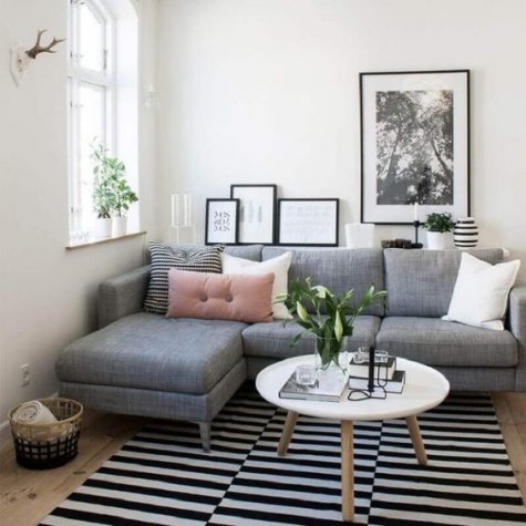 a small living room with a grey sectional sofa that takes most of space yet fulfills its function and a coffee table