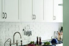 04 an all-white kitchen with a white brick backsplash for a textural feel, black countertops and dark metal handles