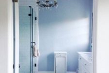 06 a blue and white bathroom with navy fishscale tiles on the floor, an elegant chandelier and white furniture looks sea-like