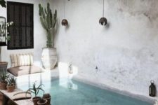 06 a minimalist pool space with a boho feel, with a living edge bench, wall lamps, potted cacti, Moroccan inspired pillows