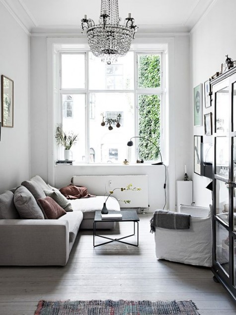 a small living room with a large sofa, a glass armoire and a crystal chandelier looks elegant and chic