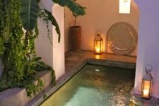 08 a small boho pool space with a pool with inner lights, candle lanterns, decor and potted plants