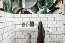 09 a chic powder room with tropical leaf wallpaper, white tiles and neutral metallics feels tropical