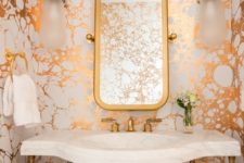 11 a bright powder room with metallic marble wallpaper, brass touches and a white stone sink