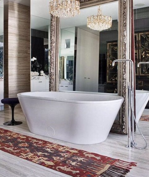 a mirror wall and an additional oversized mirror in a refined frame plus a glam chandelier for a wow effect