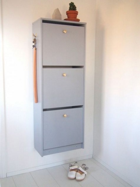 A light grey IKEA Bissa cabinet with elegant gilded knobs is a perfect entryway storage unit