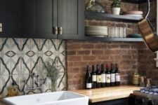 15 a moody kitchen with black cabients, light-colored butcherblock countertops with a red brick backsplash