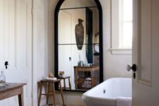 17 a chic vintage-inspired bathroom with a beautiful arched mirror in a black frame looks wow