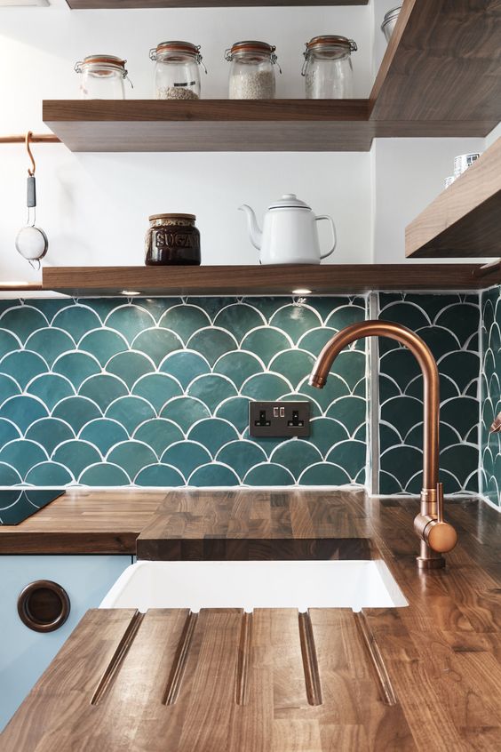 a contemporary kitchen with butcher block countertops, wooden shelves and teal fishscale tiles