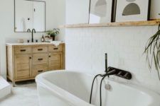 24 a neutral bathroom with an oval tub, a shelf with a duo of abstract artworks for a bolder and catchier look