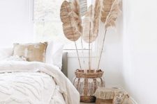 a boho Moroccan space with fringe and tassel bedding, a jute rug, dired grasses and fronds and woven baskets