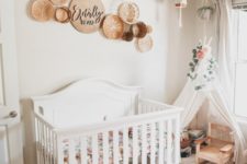 a boho nursery with a white crib, baskets on the wall, a teee for reading and some suspended plants