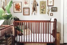 a bold boho nursery with a gallery wall, dark stained furniture, layered rugs and tropical plants in pots