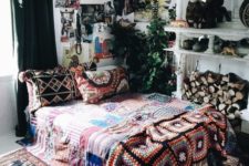 a bold boho room with much greenery hanging in pots, lots of prints and a gallery wall plus a crystal chandelier