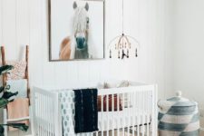 a bright boho nursery with a colorful rug, a printed basket with a lid, a macrame chandelier, colorful textiles and a horse artwork
