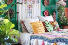 a colorful gypsy bedroom with an emerald wall,, decorative plates, colorful pillows and blankets, macrame lanterns and potted plants