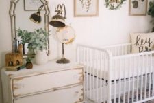 a farmhouse nursery with a white crib a shabby chic dresser, a vintage mirror and a lamp plus botanical touches